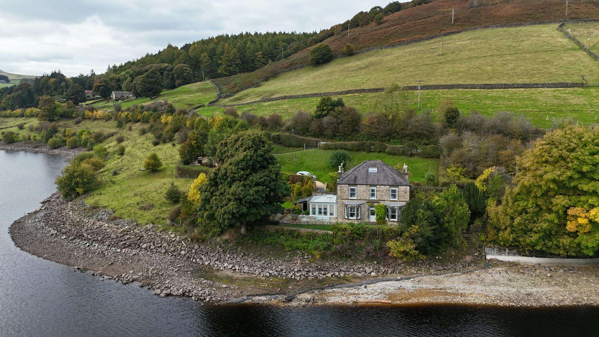 A picturesque stone house by a serene lake in the English countryside.