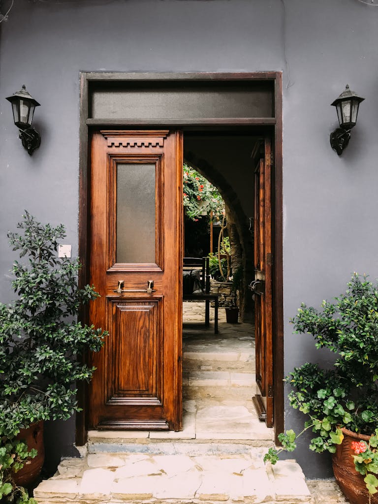 Explore a rustic wooden doorway leading to a lush courtyard in Yukarı Lefkara, Cyprus.