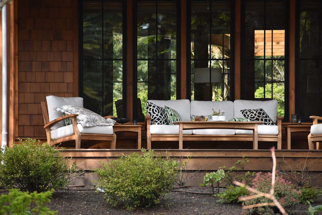 Inviting outdoor patio with comfortable wooden furniture and lush greenery.