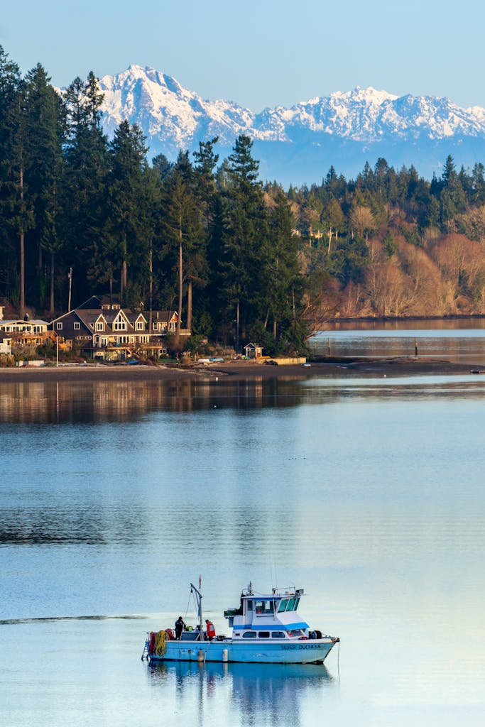 Tranquil morning scene with a fishing boat and snowcapped mountains in Washington, USA.